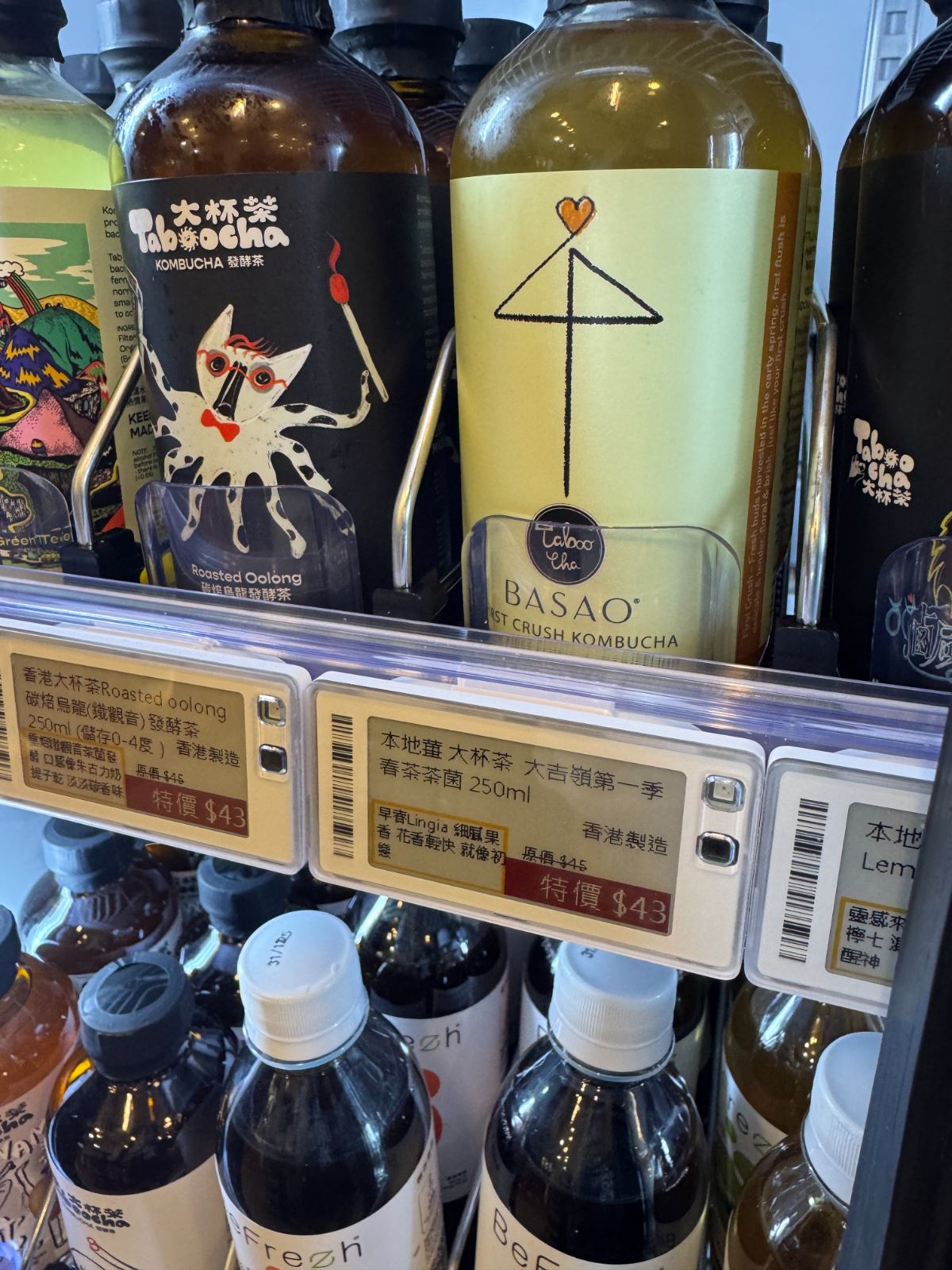 E-paper electronic shelf labels (ESL) on a chilled drinks shelf in a Hong Kong store, showing promo prices